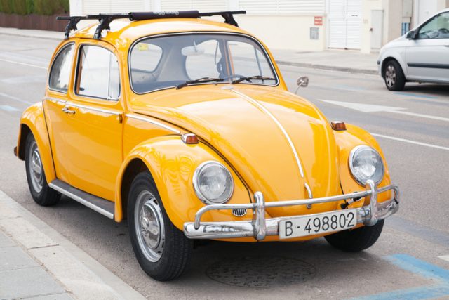 Yellow Volkswagen Kafer stands parked on the roadside.