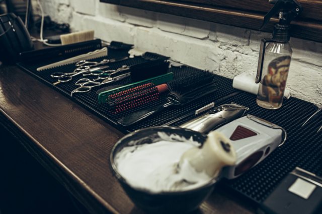 Barber shop tools on the table. Close up view shaving foam. Barber shop concept. Shaving machine, comb, scissors and different items on the table in the barber shop.
