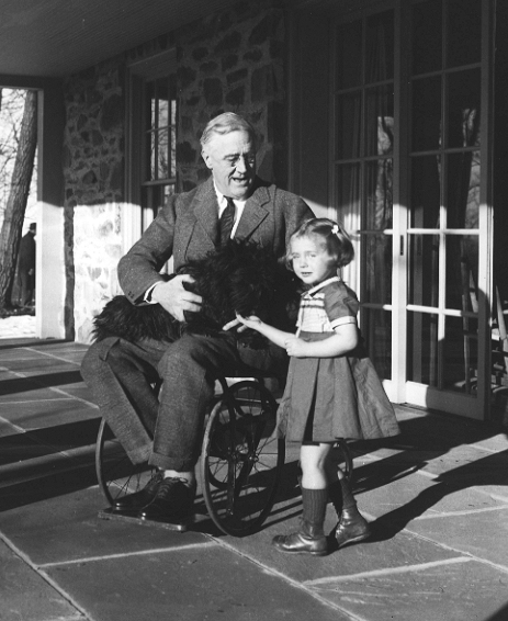 Rare photograph of Roosevelt in a wheelchair, with Fala and Ruthie Bie, the daughter of caretakers at his Hyde Park estate. Photo taken by his cousin Margaret Suckley in February 1941.