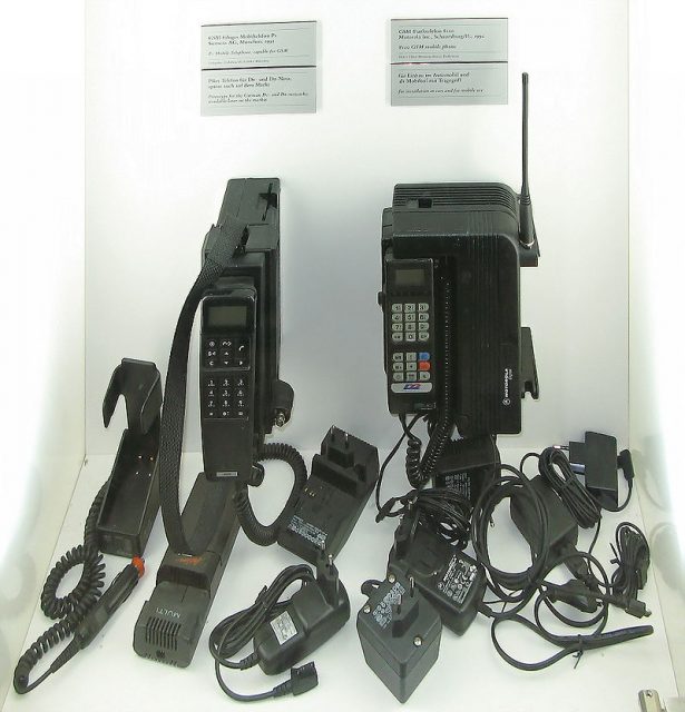 Two 1991 GSM mobile phones with several AC adapters Photo by Clemens PFEIFFER CC BY 2.5