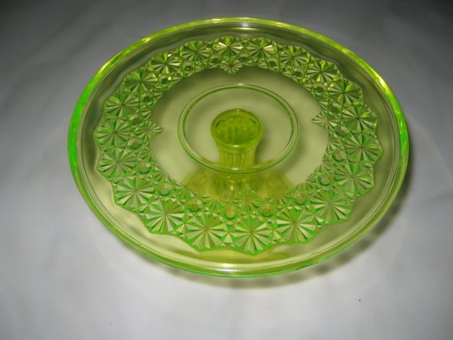 A uranium glass cakeplate glowing under UV light. Photo by Z Vesoulis CC BY-SA 2.5