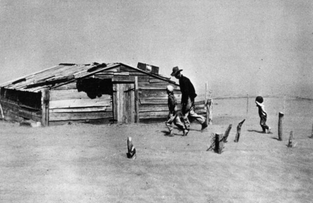 A farmer and his sons walk in a dust cloud