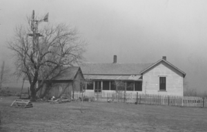 Kansas farm house, in a field with a windmill, during the dustbowl era, 1935