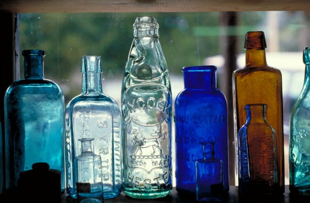 Colorful vintage medicine bottles in an antique store window.