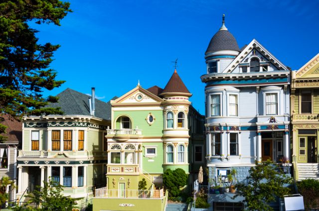 A view of three elaborate victorian houses taken from Alamo Square in San Francisco.