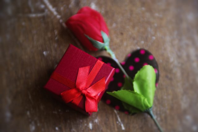 Red rose with red boxed gift.