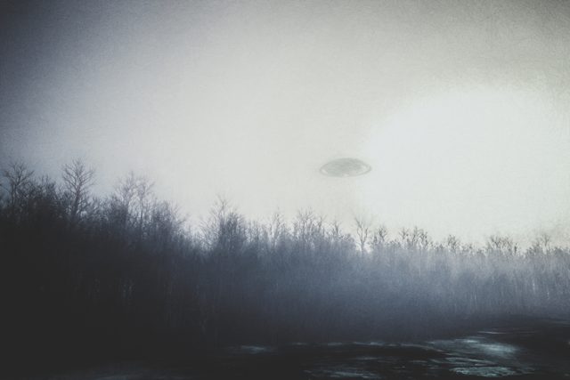 UFO flying over forest at night.