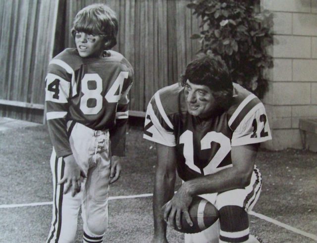 Photo of football player Joe Namath and Mike Lookinland (Bobby) from the television program The Brady Bunch. When Bobby brags to his friends that he knows Joe Namath personally, he has to find a way to prove what he’s been saying.
