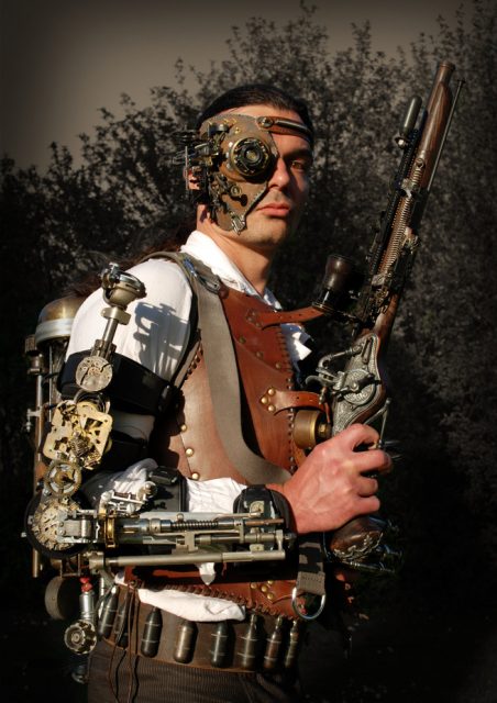 Steampunk outfit with leather vest, heavy gun, vambrace, backpack time machine, mask, and Victorian clothes. Photo by Alexander Schlesier CC BY-SA 3.0