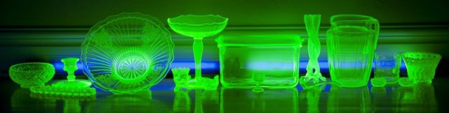 Various Vaseline glassware glowing under UV black lights. Photo by Realfintogive CC BY-SA 3.0