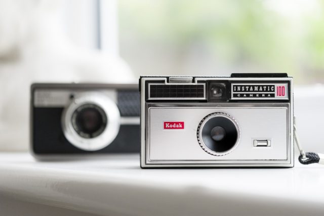 Kendal, UK – May 27, 2015: Close-up of the iconic Kodak Instamatic 100 from the 1960s, flanked in the defocussed background by a top of the range Instamatic 500.