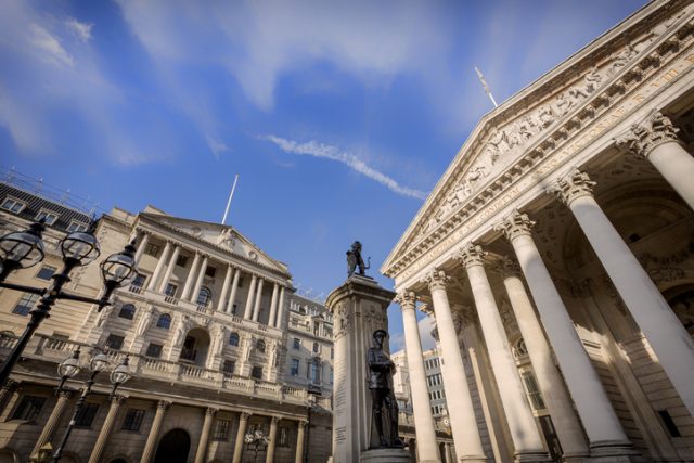 Low angle view of the main facades of the Bank of England and London Stock Exchange and the London Troops memorial at Bank Junction in the City of London. London.