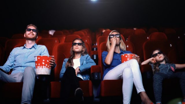 Closeup view of young family watching a 3D movie at movie theater