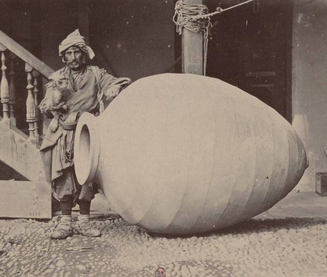 A man stands next to an enormous container used to store wine in Kakheti, Georgia, 1881.