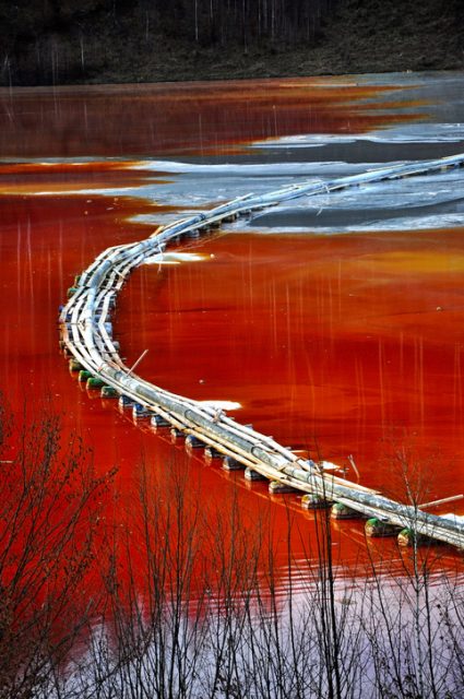 Red polluted industrial waste lake at Geamana in the Carpathian Mountains, Romania