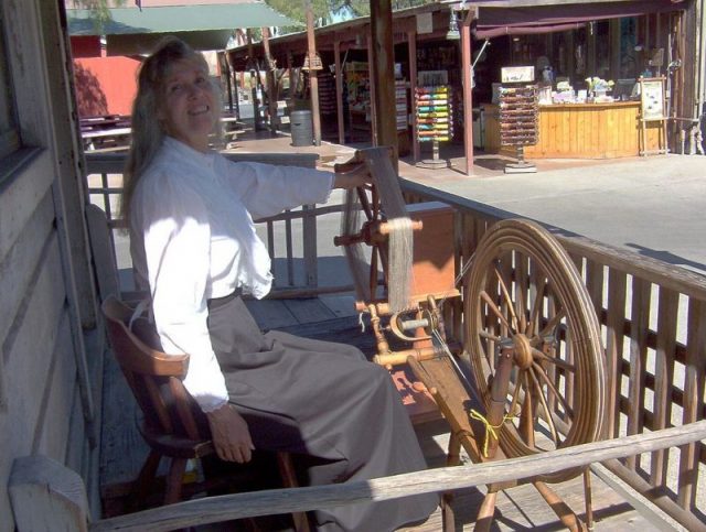 Spinner Charlene Parker with weasel (on left) and spinning wheel (on right) at Knott’s Berry Farm. Photo by DTParker1000 CC BY-SA 4.0
