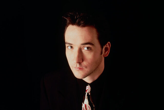 Promotional photo of John Cusack against a black background