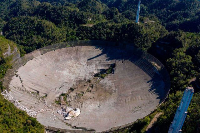 This aerial view shows the damage at the Arecibo Observatory after one of the main cables holding the receiver broke in Arecibo, Puerto Rico, on December 1, 2020. – The radio telescope in Puerto Rico, which once starred in a James Bond film, collapsed Tuesday when its 900-ton receiver platform fell 450 feet (140 meters) and smashed onto the radio dish below. (Photo by Ricardo ARDUENGO / AFP) (Photo by RICARDO ARDUENGO/AFP via Getty Images)
