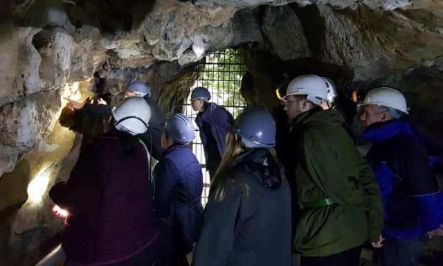 Members of the Subterranea Britannica group check out the witches’ marks at Creswell Crags. Credit: Historic England