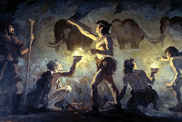 Early peoples painting woolly mammoths on a cave wall