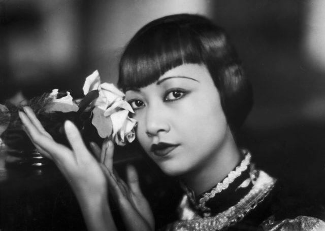 Photograph of Anna May Wong holding a flower