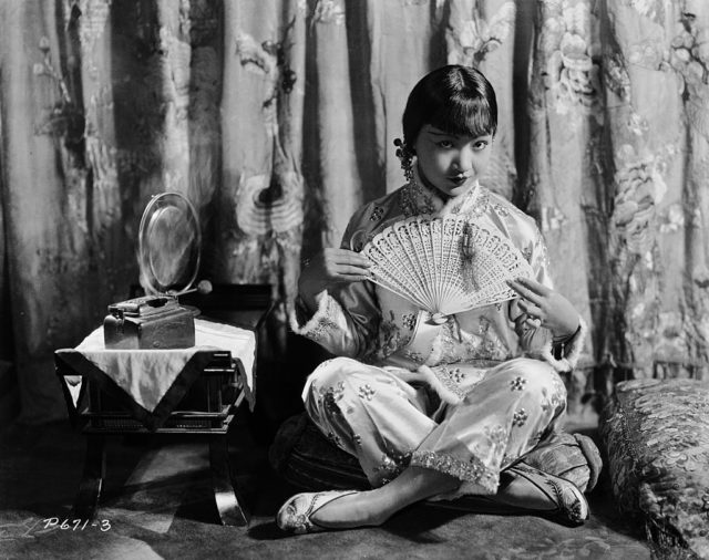 Anna May Wong sitting cross-legged on a cushion