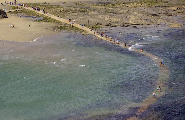 People crossing the tidal causeway from St Michael's Mount to Marazion as the tide comes in, Marazion, England.