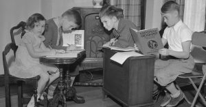 Children sitting around a radio for school lessons in 1937