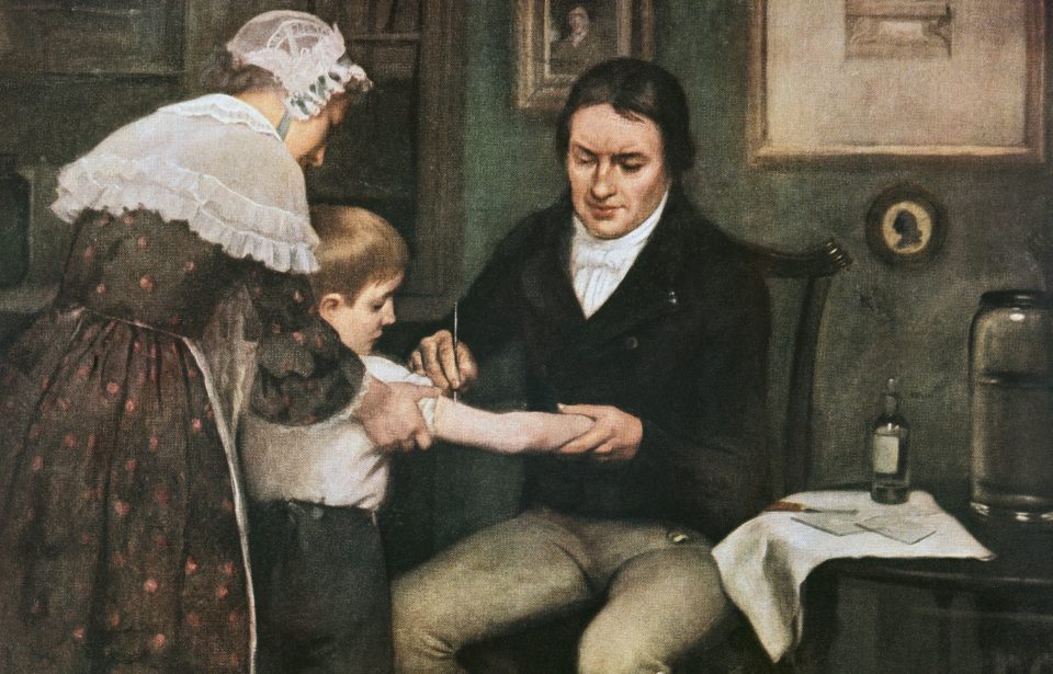 Dr. Edward Jenner performing his first vaccination against smallpox on James Phipps, a boy of eight, oil on canvas by Ernest Board. (Photo Credit: DEA Picture Library / Contributor)