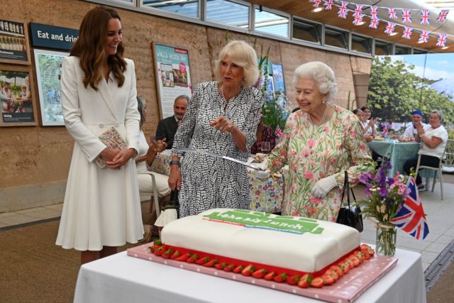 Queen Elizabeth II cutting a cake with a sword alongside Kate Middleton and Camilla, Duchess of Cornwall