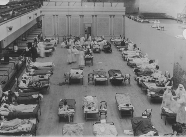 An overhead view of a makeshift infirmary filled with patients, beds and nurses