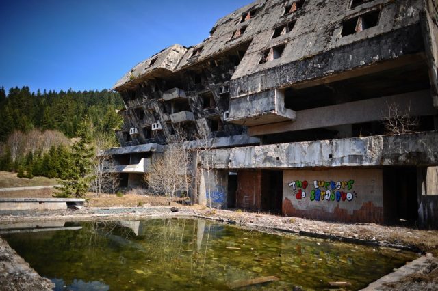 Decrepit building with an algae-filled pool in the front 