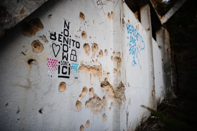 Cement wall with graffiti and bullet holes in it