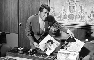 Dean Martin holding a vinyl record with his face on it