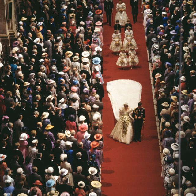 Diana being walked down the aisle while guests look on