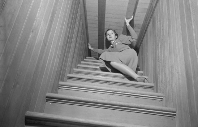 A blind stairway on inside of the Winchester Mystery House. Miss Maxine Upham is shown in photo.