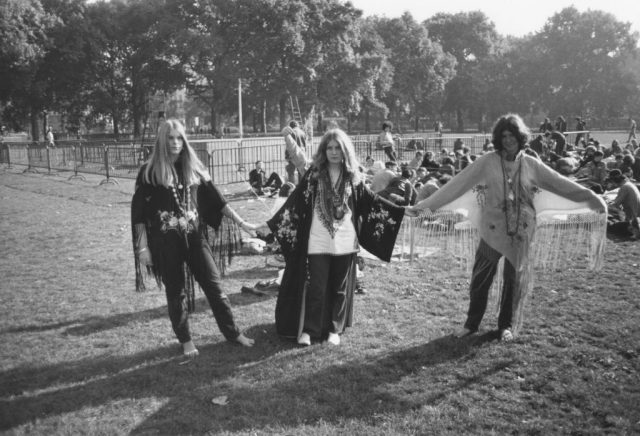 Three female hippies holding hands in a park