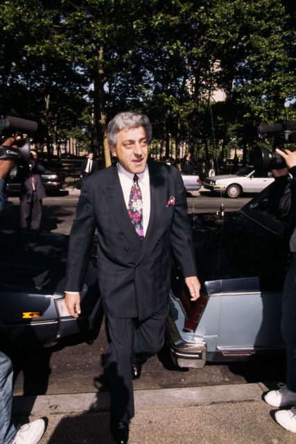 Mobster John D'Amico walking up concrete steps that are between two cars