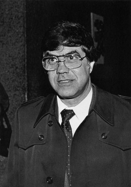 Joseph Lombardo wearing a trench coat and wire-rimmed glasses