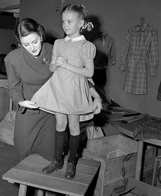 Natalie Wood being fitted in a plaid dress by a woman