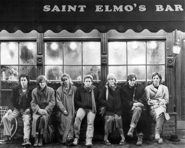 The cast of St. Elmo's Fire sitting in from of Saint Elmo's Bar