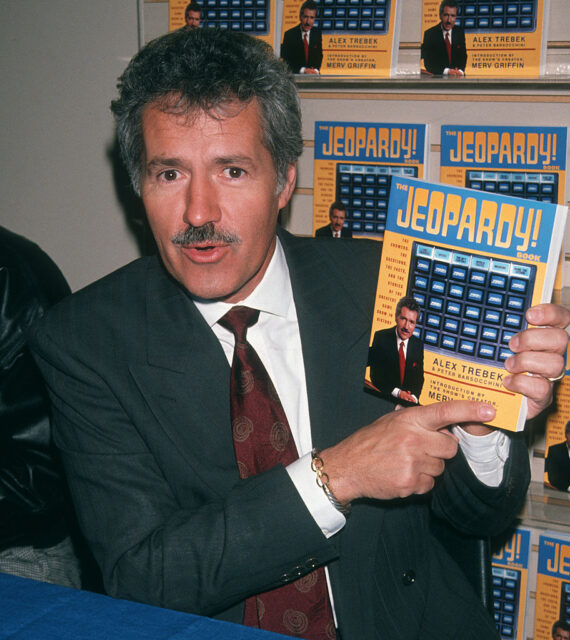 Alex Trebek holding his own book