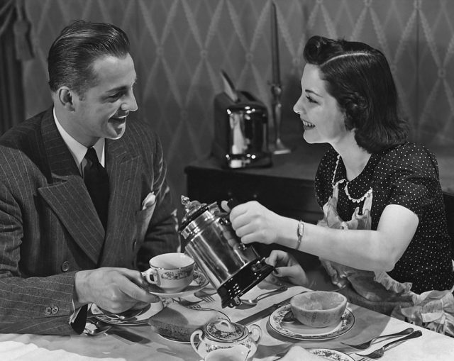 A smiling woman pouring coffee for a man. (Photo Credit: Keystone View Company/Archive Photos/Getty Images)