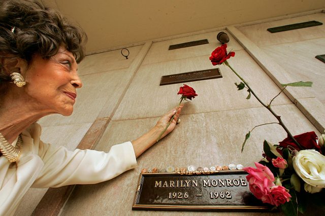 Elizabeth Poncher holding a rose in front of her husband's crypt