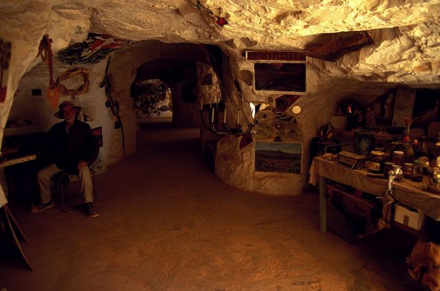 Man sitting in a dimly lit underground dwelling