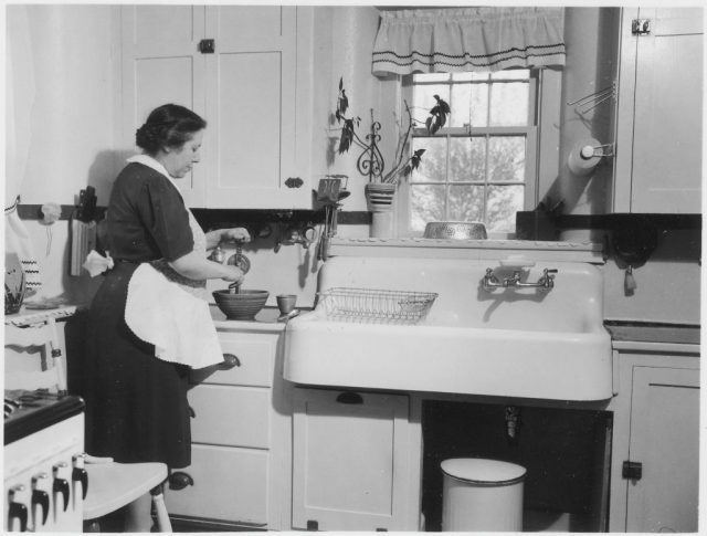 Woman standing to the left of a kitchen sink