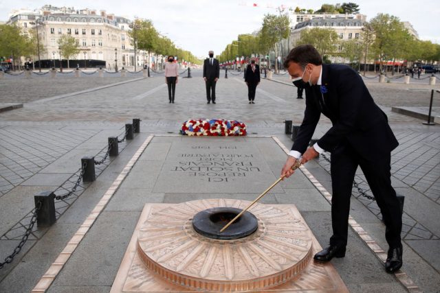 French President Emmanuel Macron lights up the flame at the tomb of the Unknown Soldier during a ceremony marking the 76th anniversary of Victory in Europe (VE-Day), marking the end of World War II in Europe, in Paris on May 8, 2021. (Photo Credit: CHRISTIAN HARTMANN/POOL/AFP via Getty Images)