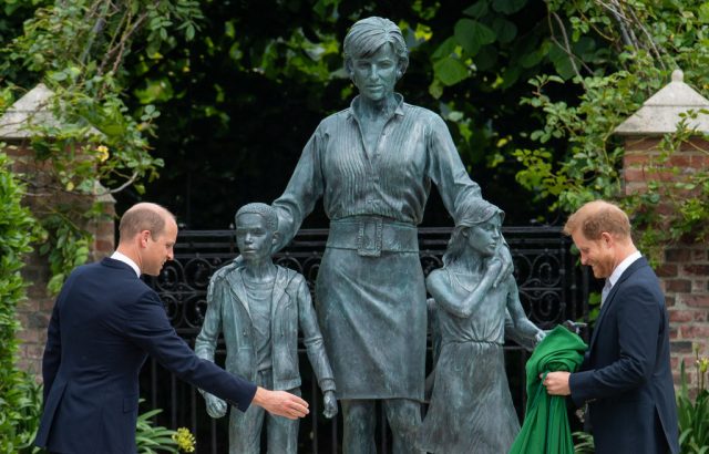 Princes William and Harry standing in front of the Princess Diana statue