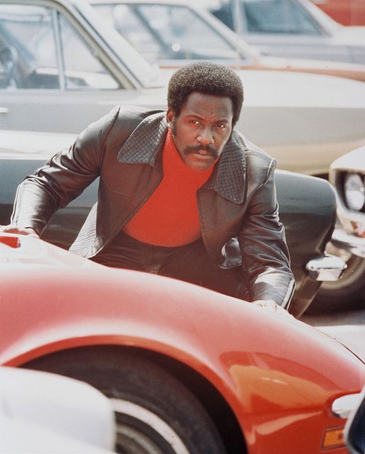 Richard Roundtree, US actor, crouching behind a red sports car in a publicity still issued for the film, ‘Shaft’, 1971. (Photo Credit: Silver Screen Collection/Getty Images)