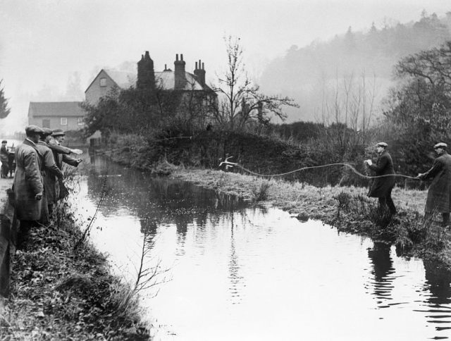 Policemen standing along a pond